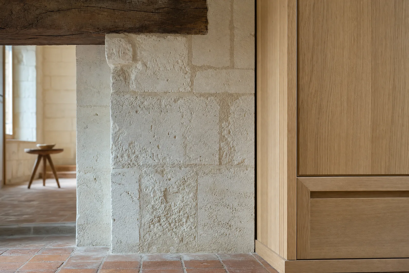 Detail d'une renovation en Val de Loire : un mur de tuffeau nettoye rencontre une menuiserie de chene clair posee au joint creux