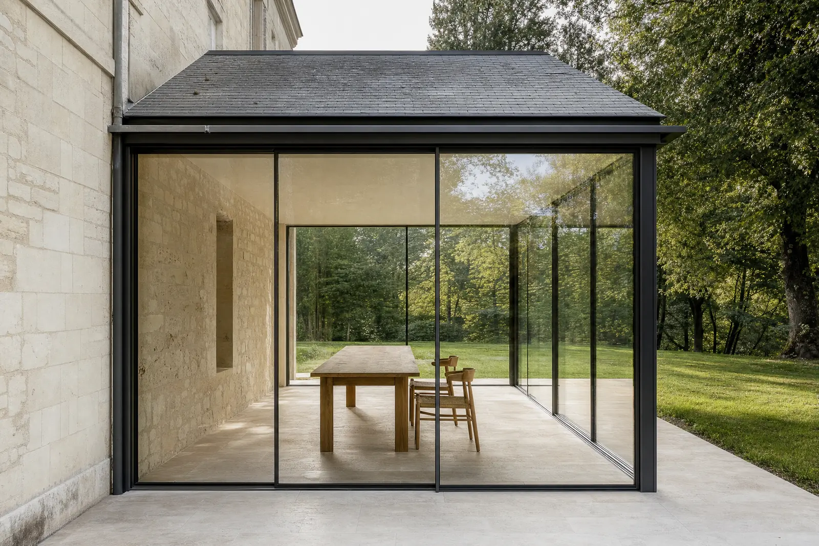 Piece de jardin contemporaine greffee sur une maison de pierre du Val de Loire, ouverte de plain-pied sur la pelouse et les arbres