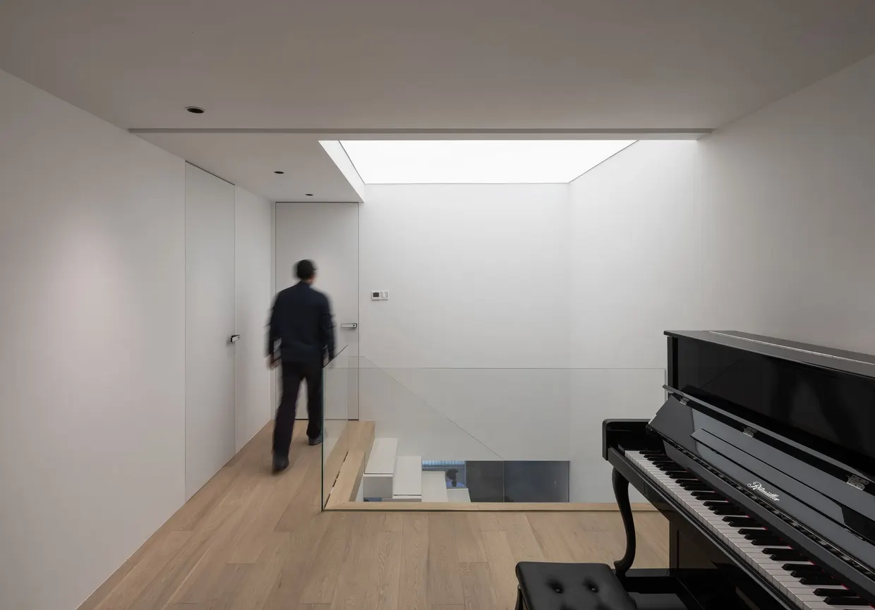 Palier haut du Loft Zàntíng à Shanghai et piano sous la lumière du puits, aménagement par Atelier Cantera
